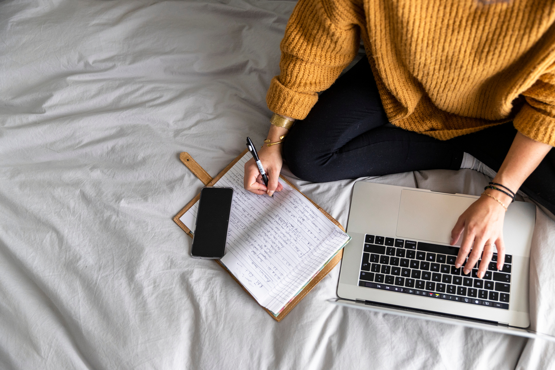 Directly above woman writing notes while in an online meeting